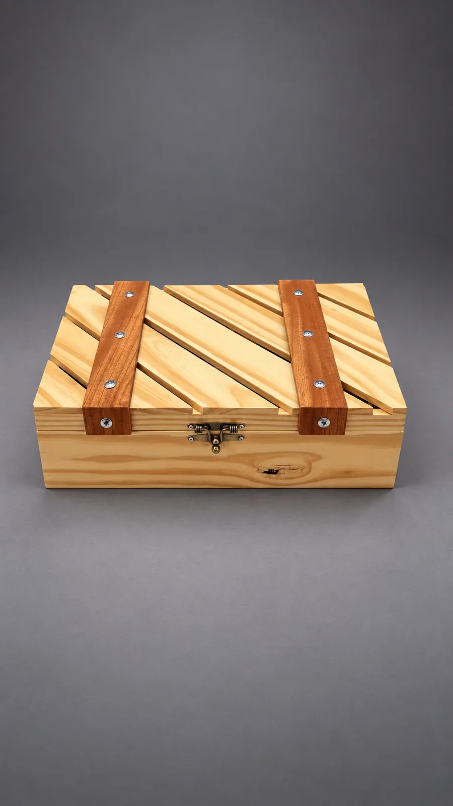 Binomio Tinto cerrado: la caja de pino con la tapa calada, las dos tiras de madera oscura y el broche de bronce